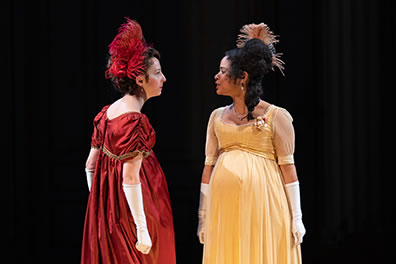 Production photo of Becky and Amelia, both pregnant in Regency gowns, staring each other down.